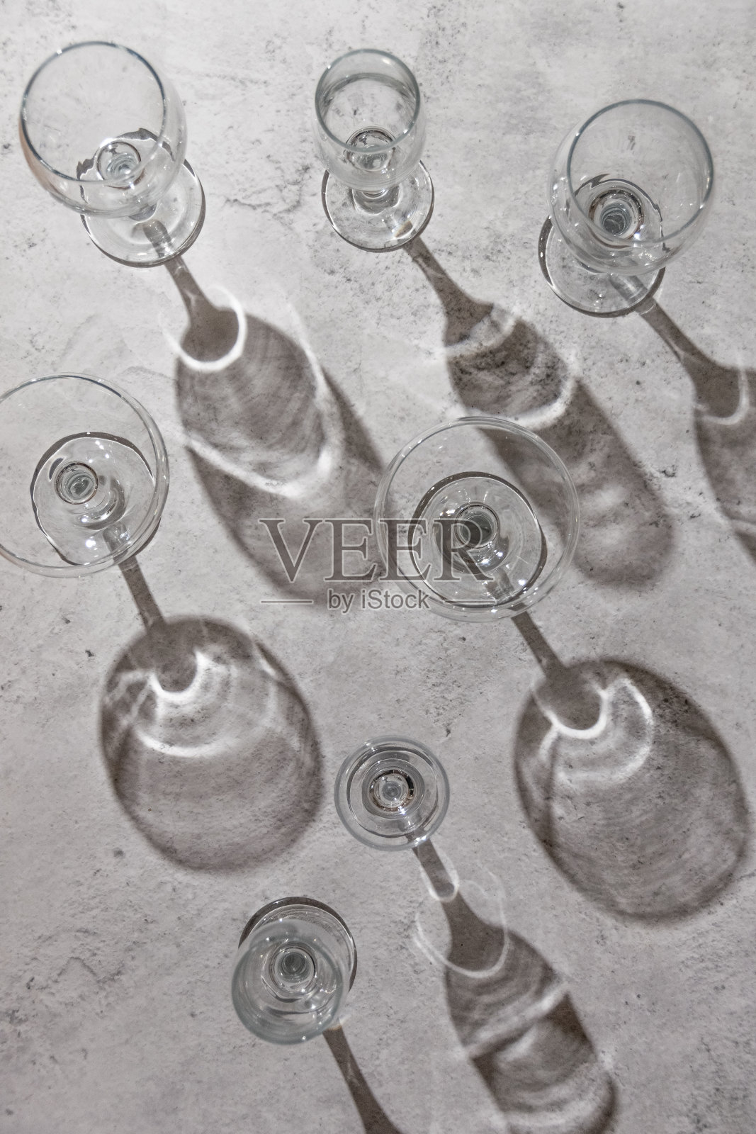 空的酒杯在灰色的背景上。阳光直射，审美静物照片摄影图片