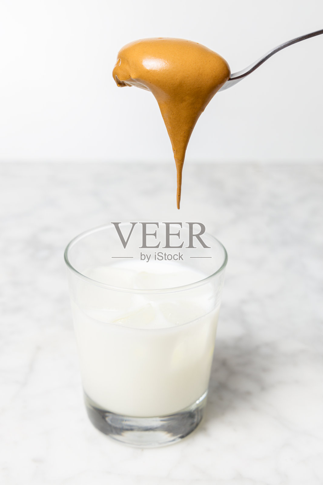 将鲜奶油倒入杯中，加入牛奶和冰块。Dalgona咖啡准备照片摄影图片