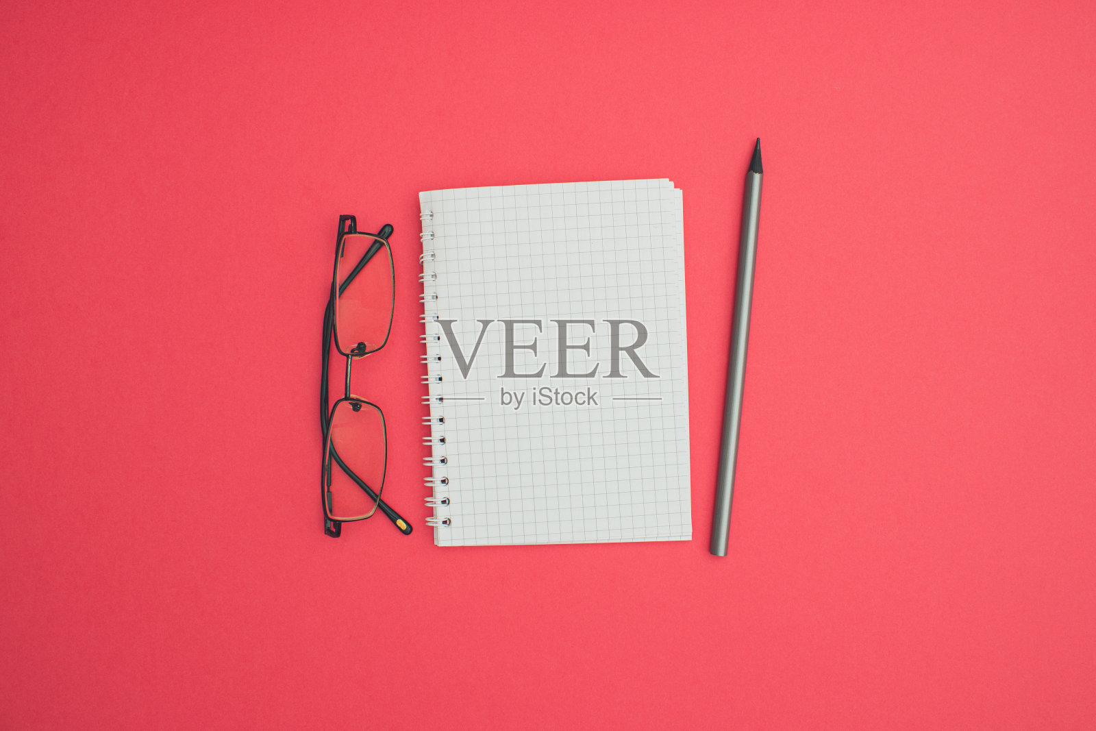 商务A6笔记本线材装订模拟空白模板设计思路。眼镜和灰色石墨铅笔模型在柔和的粉红色背景。复制消息布局的空间模板设计。照片摄影图片