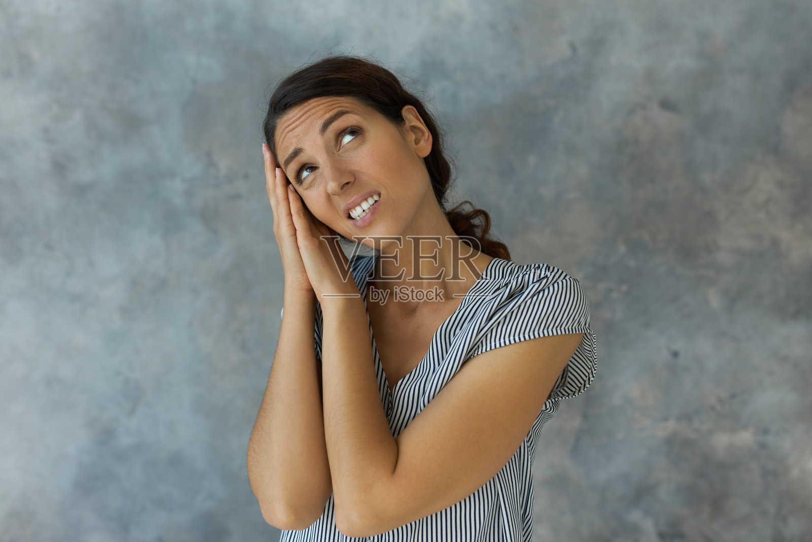 在画室里拍摄的女性睡姿的肖像中，她将手掌压在头下，听到楼上的邻居发出的噪音时，她看起来很失望，抬起头，脸上露出不满的表情照片摄影图片