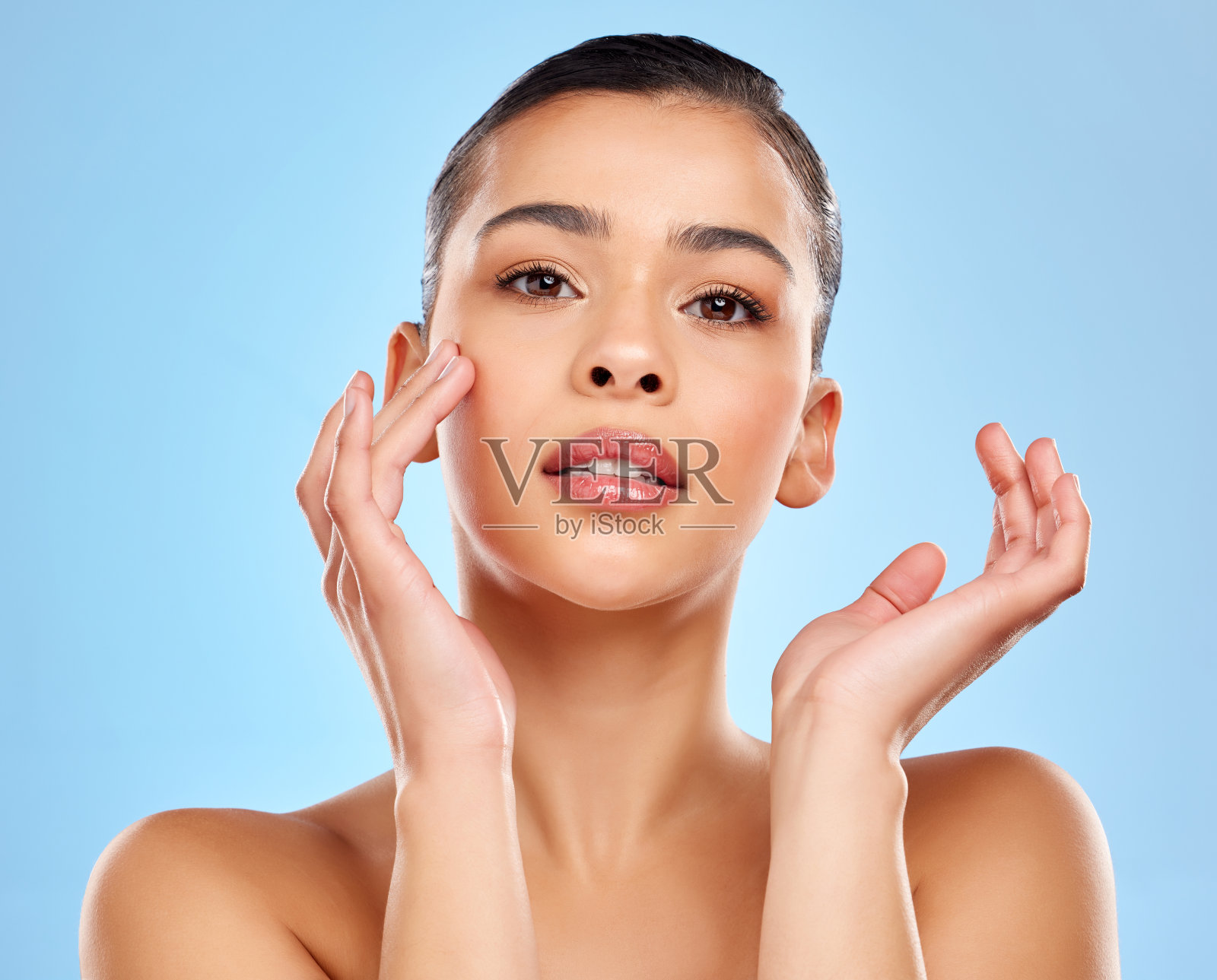 一个迷人的年轻女子在蓝色背景下摆姿势的工作室肖像照片摄影图片