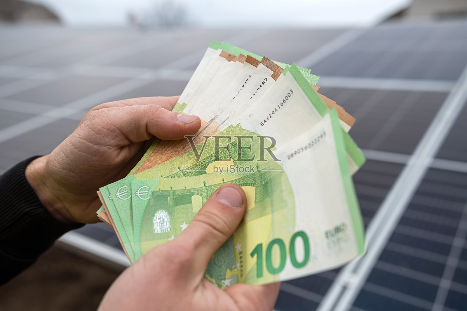 强壮的男性工人的手拿着欧元钞票完成工作。照片摄影图片