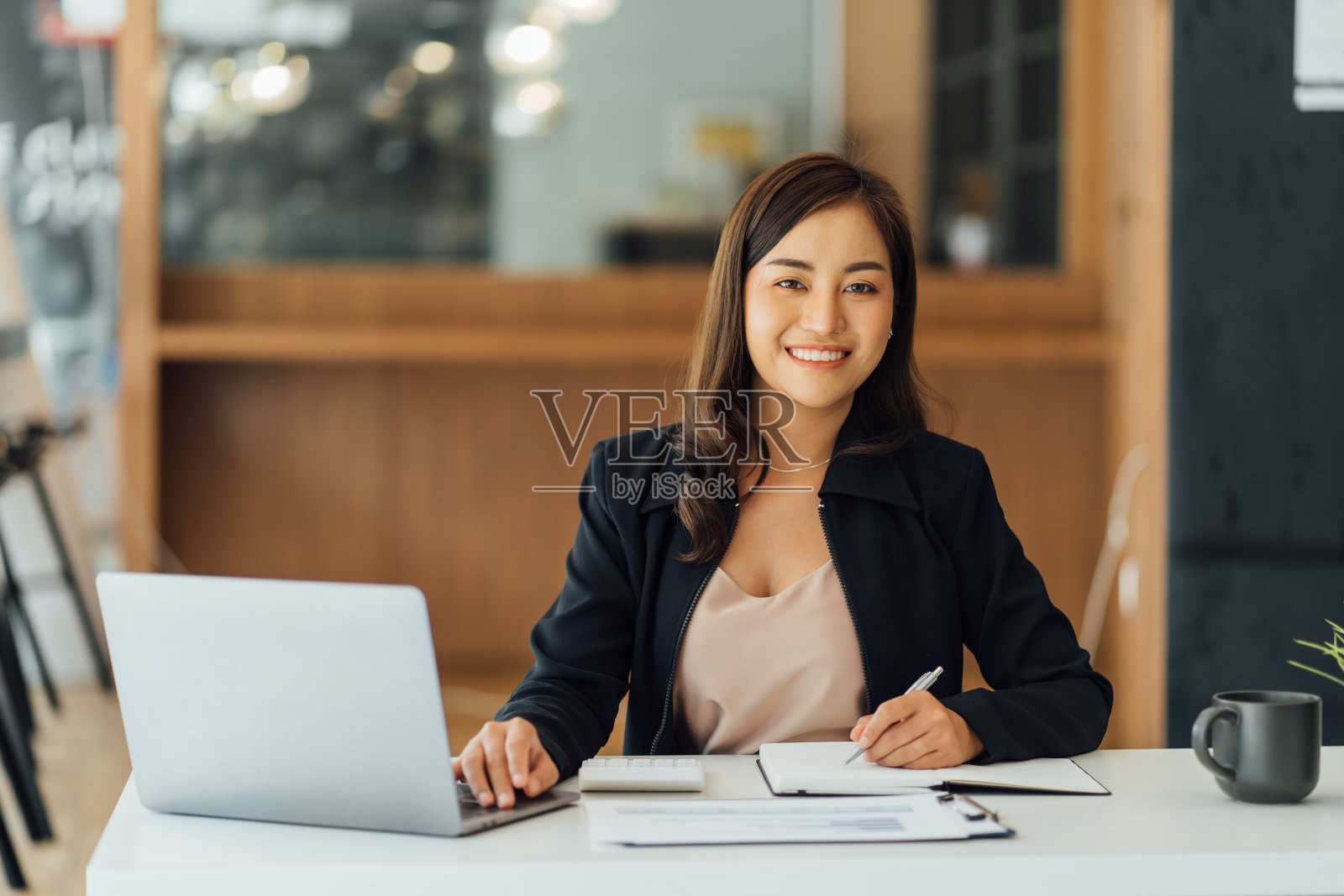 美丽的亚洲女商人分析图表使用笔记本电脑计算器在办公室。照片摄影图片