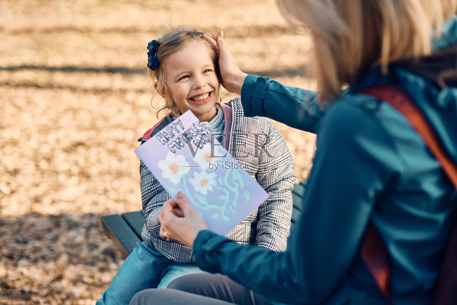 快乐的女儿在母亲节用贺卡给妈妈一个惊喜。照片摄影图片