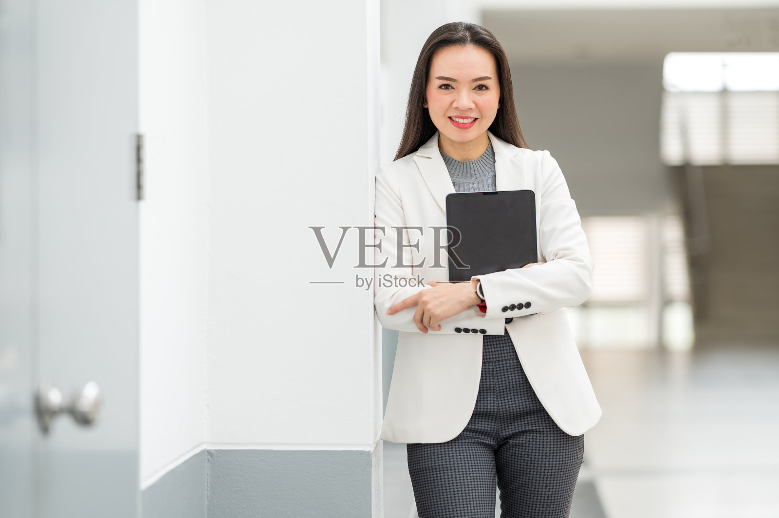 一幅成功的亚洲女商人的肖像，穿着轻松的商务套装，在商业大楼之间拿着平板电脑照片摄影图片