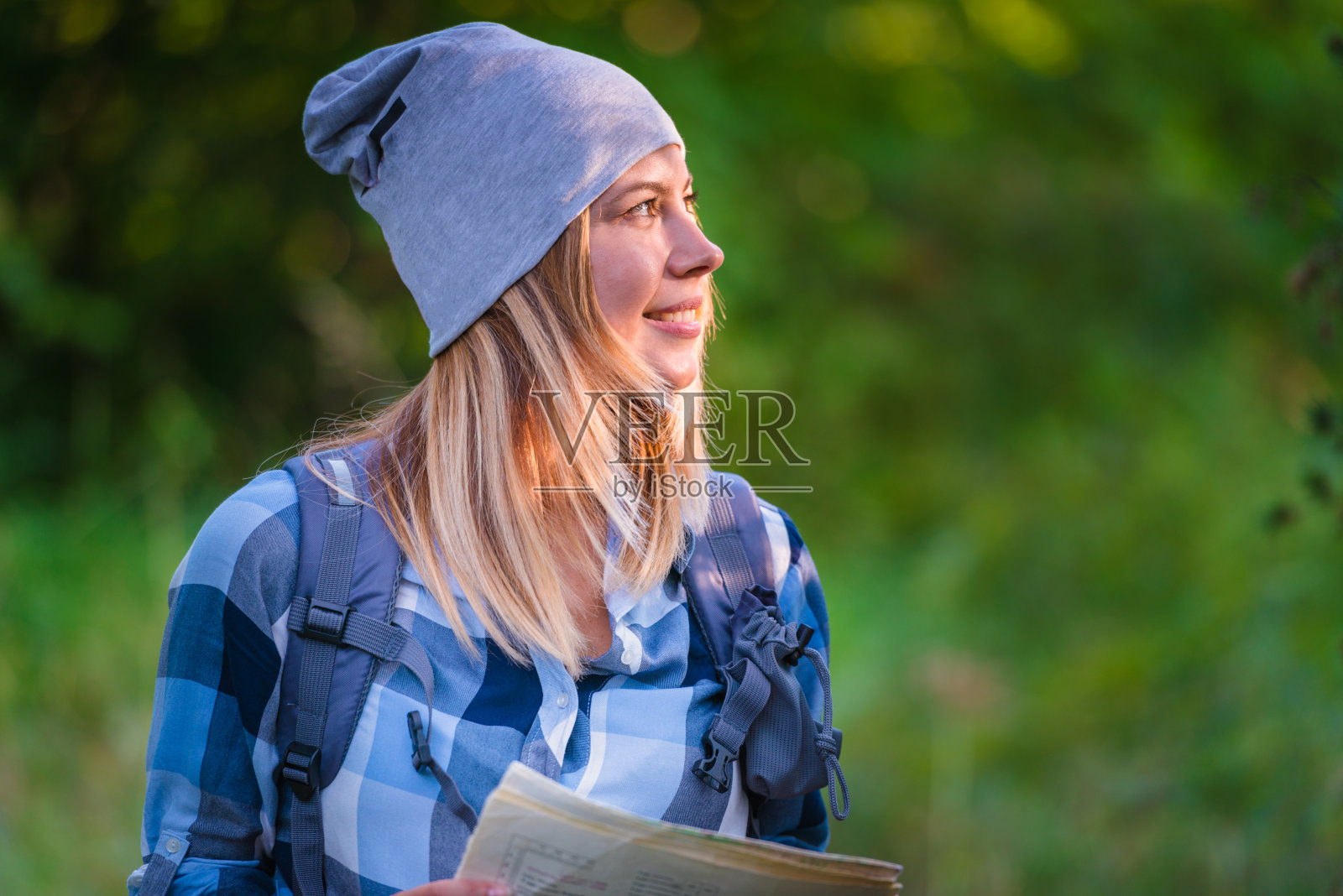 年轻女子拿着地图独自走在树林里。夏季登山概念照片摄影图片
