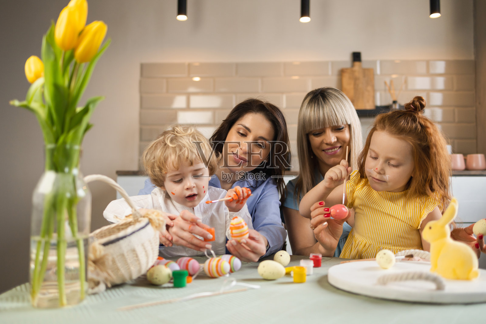 两位母亲和她的孩子用颜料装饰复活节彩蛋照片摄影图片