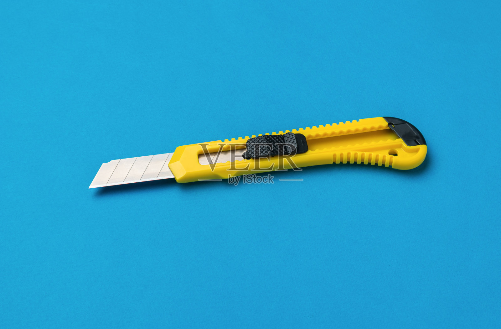 黄色和黑色文具刀在明亮的蓝色背景上。照片摄影图片