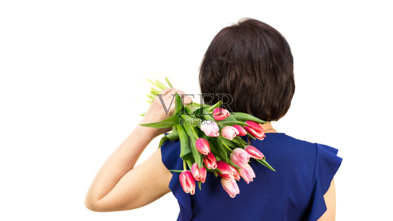 一名身着蓝色上衣的女子肩上扛着一束郁金香，从背后眺望照片摄影图片