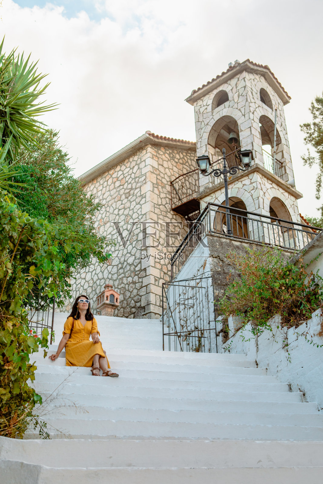 年轻的旅行家，穿着黄色的衣服走在希腊古城。照片摄影图片