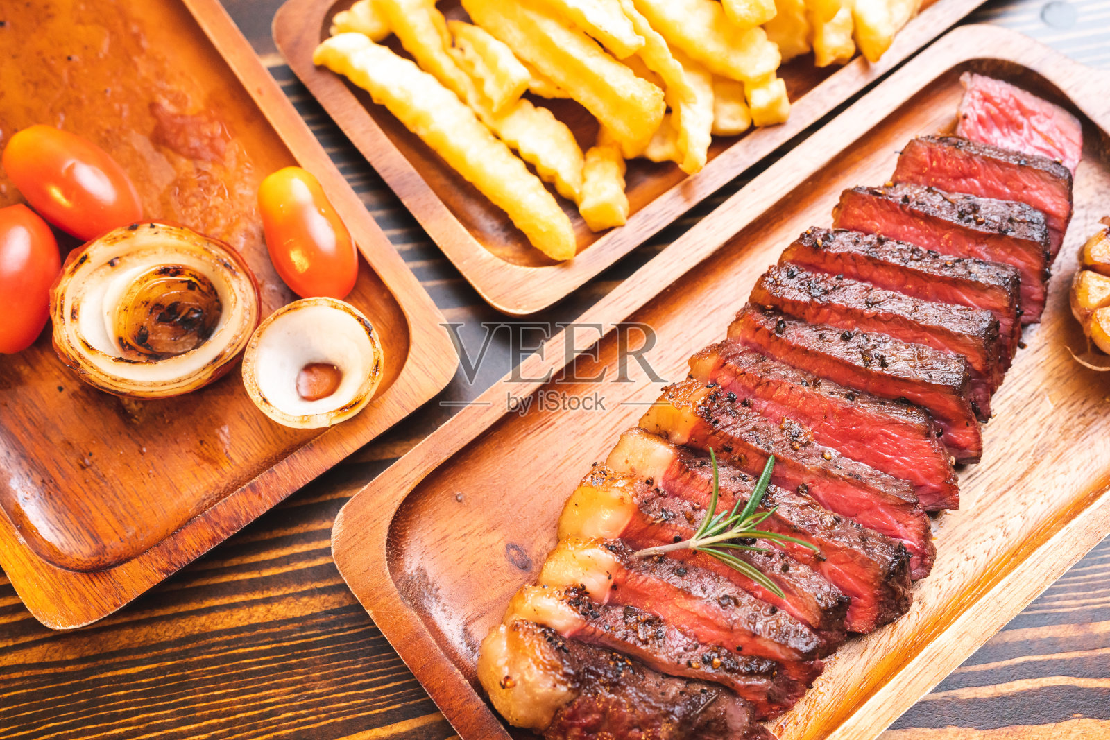 牛排装在木盘上，配以迷迭香香草和胡椒，新鲜的烤肉食物为晚餐做的，用盐和蔬菜切成的皮甘哈或牛里脊照片摄影图片