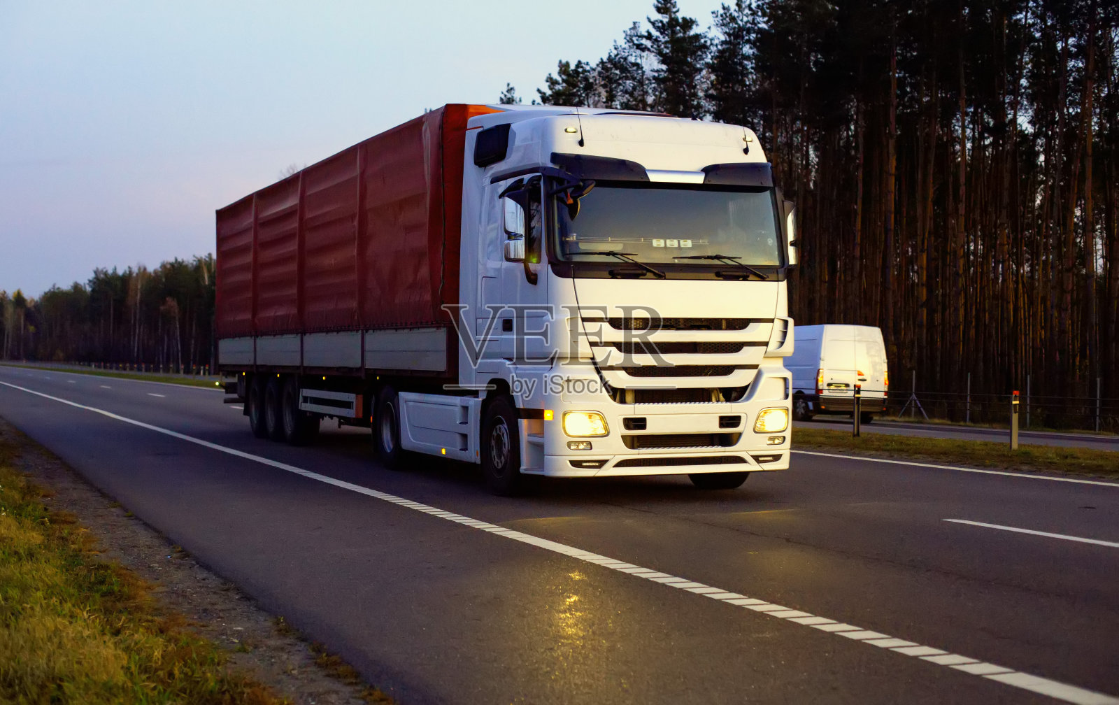 一辆漂亮的卡车，带着一辆拖车，映衬着黄昏前的夕阳。卡车司机工作和休息制度的概念。违规罚款照片摄影图片