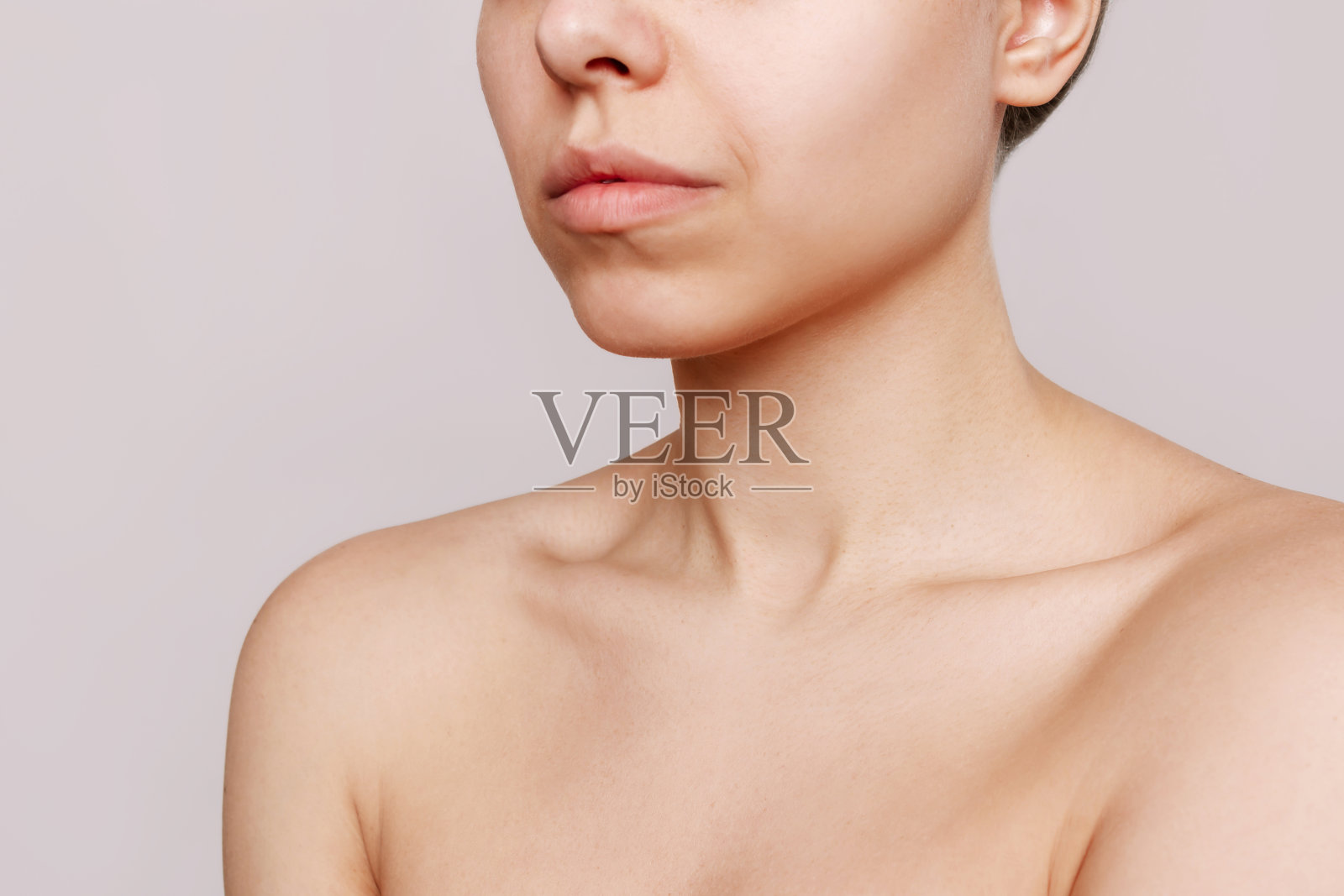 裁剪镜头的一个年轻的白人妇女与突出的锁骨孤立在米色的背景照片摄影图片