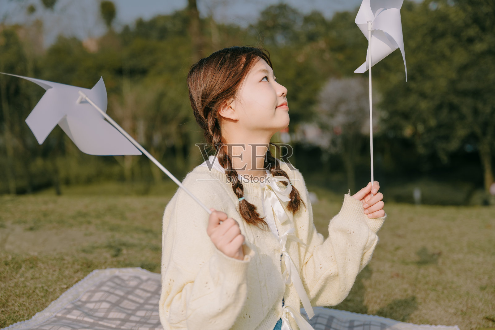 一个美丽的亚洲女孩和一个纸风车在黄昏的草坪上照片摄影图片