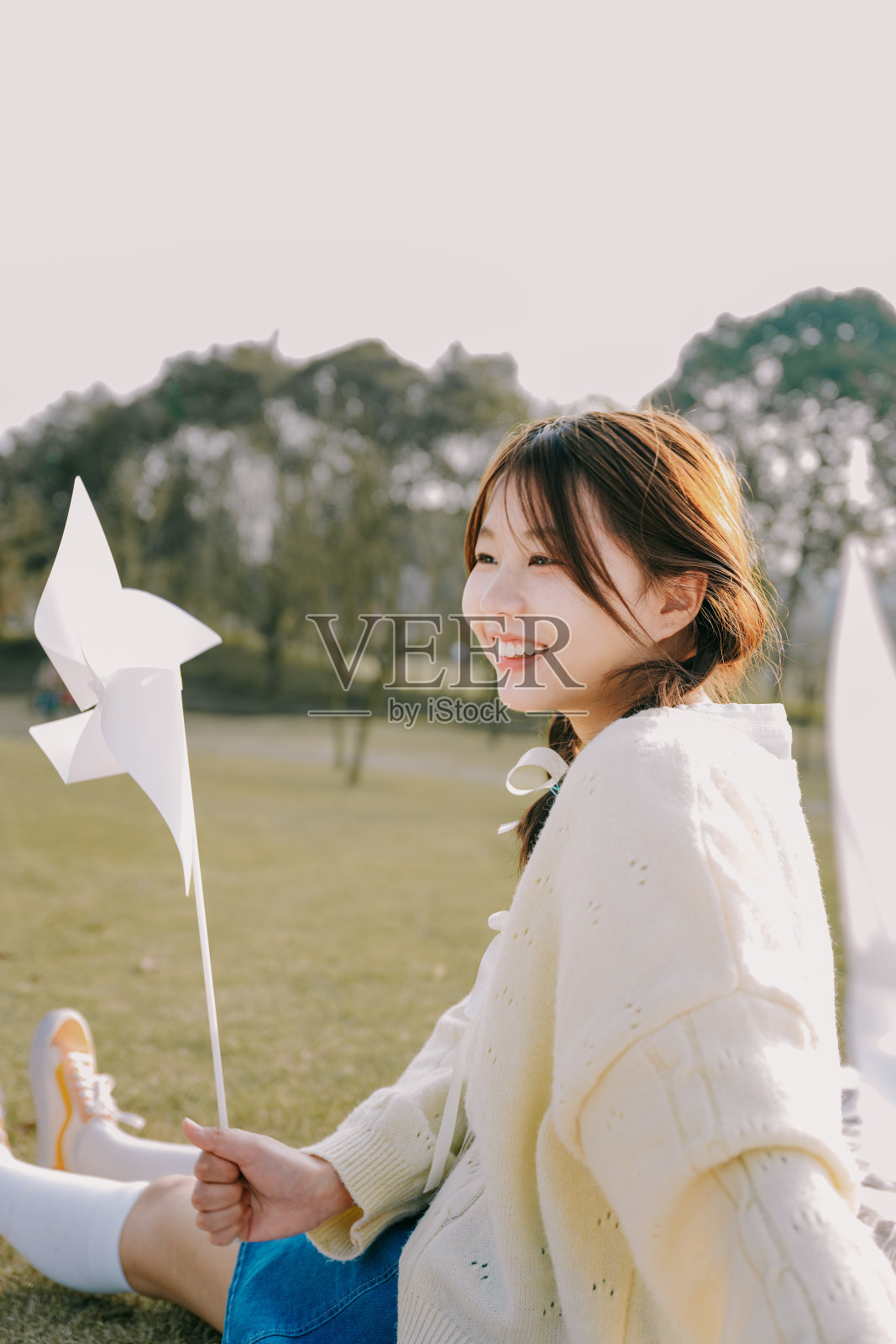 一个美丽的亚洲女孩和一个纸风车在黄昏的草坪上照片摄影图片