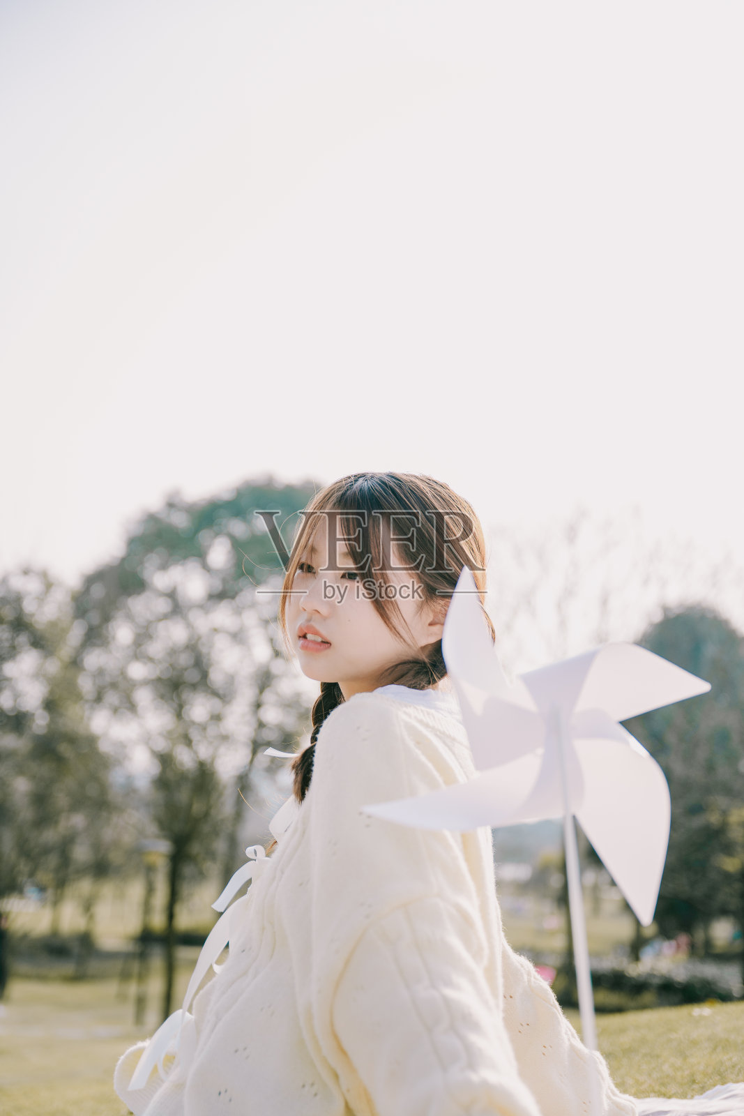 一个美丽的亚洲女孩和一个纸风车在黄昏的草坪上照片摄影图片