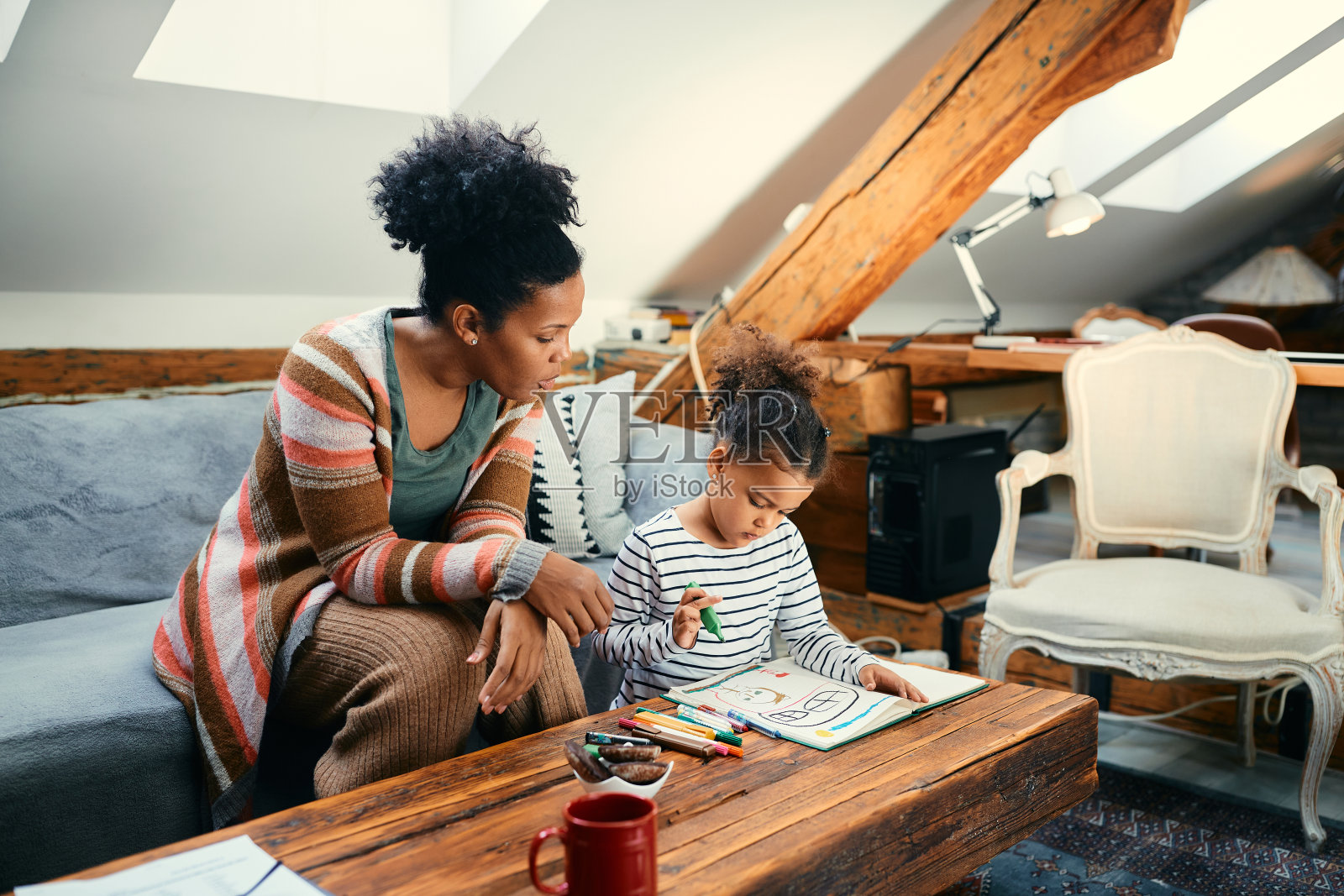 富有创造力的非洲裔美国小女孩和她的母亲在家里画画。照片摄影图片