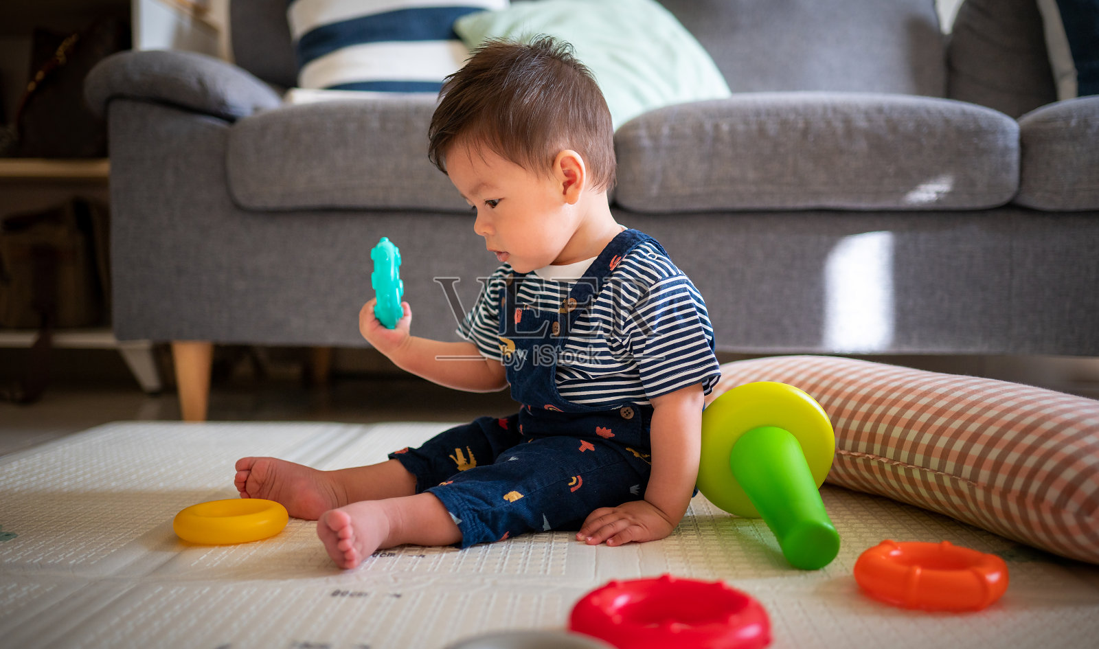 男婴坐在家里的客厅地板上的婴儿安全软垫上玩耍照片摄影图片