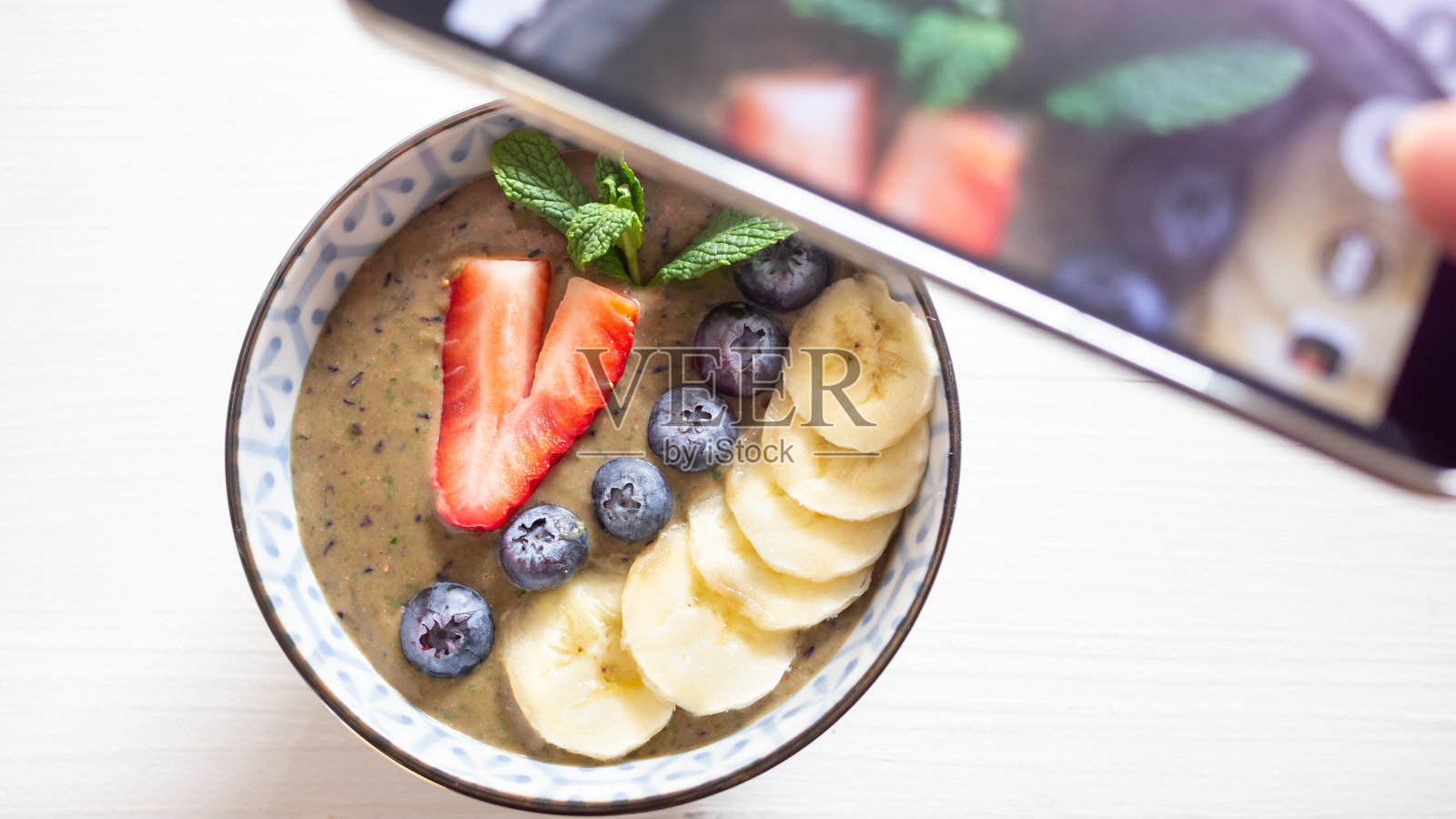 一个手机在一个f浆果素食奶昔早餐碗，使照片。照片摄影图片