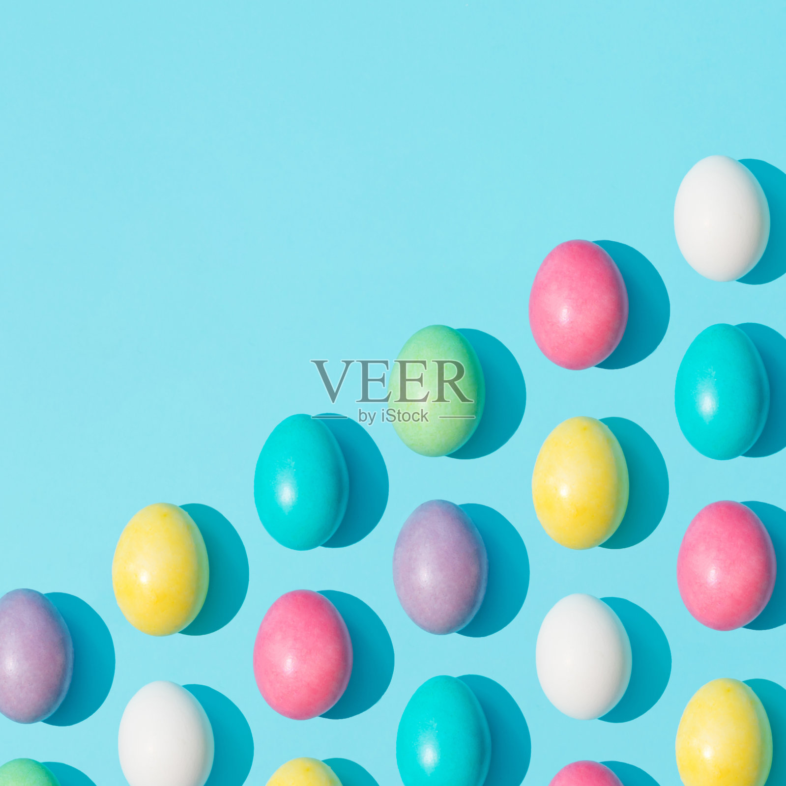 时尚的多彩充满活力的复活节彩蛋图案在明亮的蓝色背景。最小的复活节的概念。创意食品平铺构图。照片摄影图片