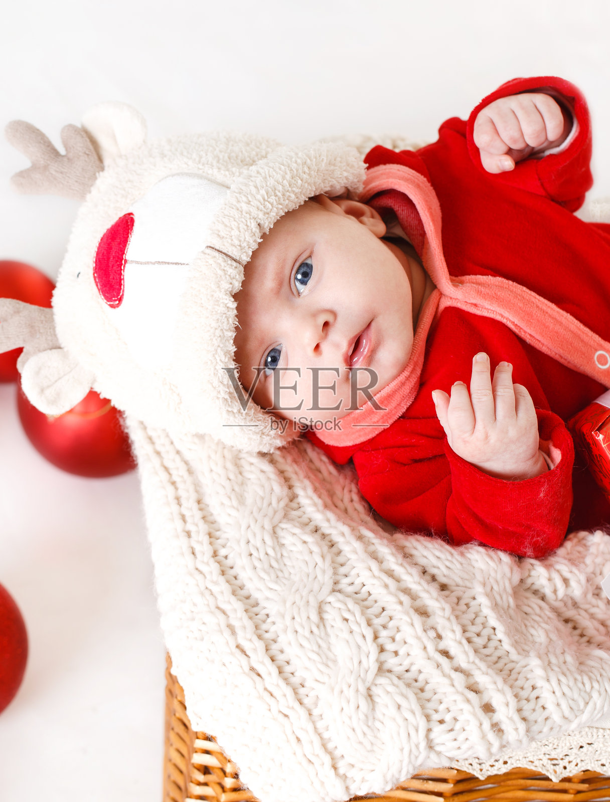 穿着圣诞老人服装的可爱小婴儿躺在篮子里照片摄影图片
