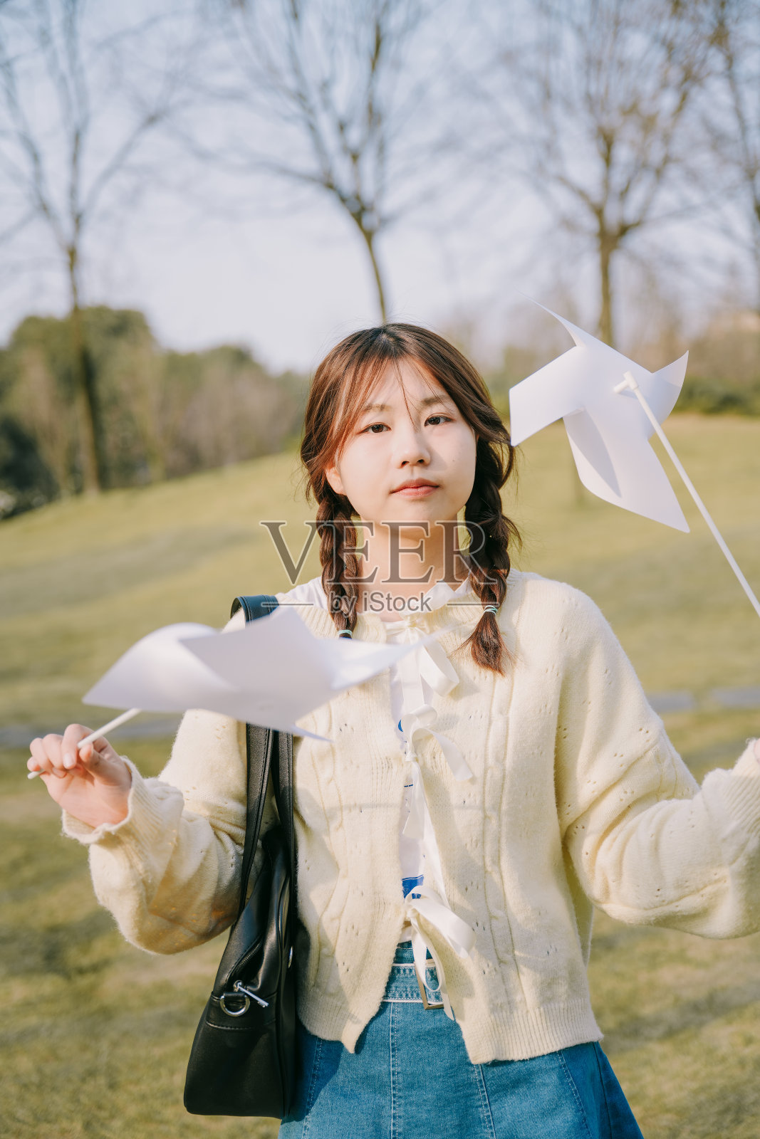 一个美丽的亚洲女孩和一个纸风车在黄昏的草坪上照片摄影图片