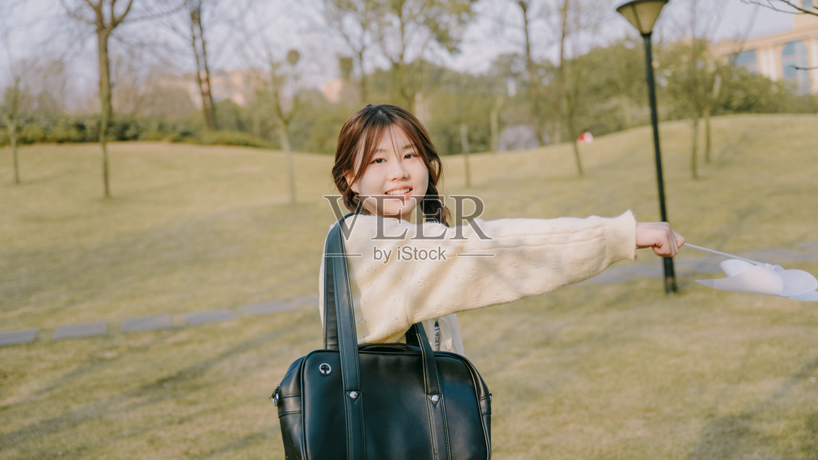 一个美丽的亚洲女孩和一个纸风车在黄昏的草坪上照片摄影图片