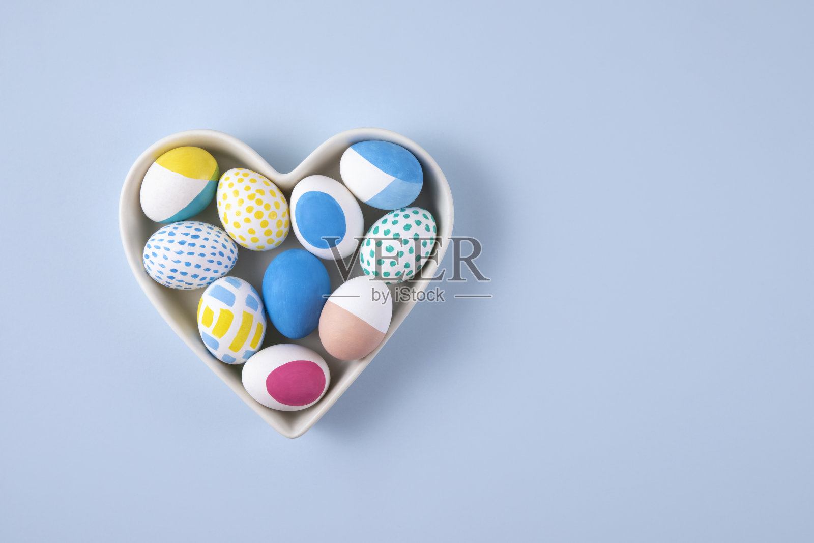 在蓝色背景的心形碗的复活节彩蛋照片摄影图片