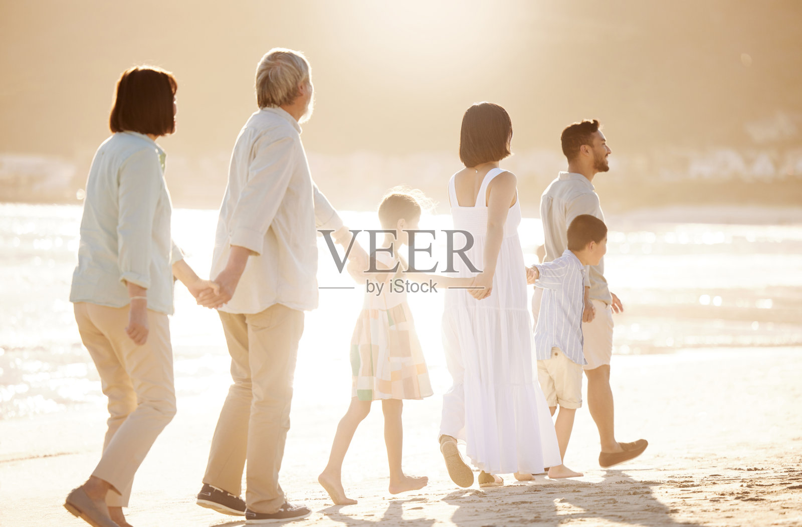 一个幸福的、多元的、多代同堂的家庭在海滩上的全身像照片摄影图片