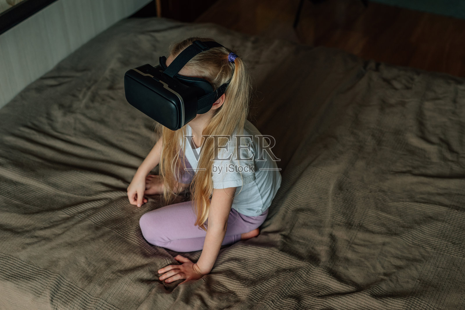 小女孩在家里戴着虚拟现实的VR眼镜看视频，玩游戏。现代的孩子很精通技术革新。一代α照片摄影图片