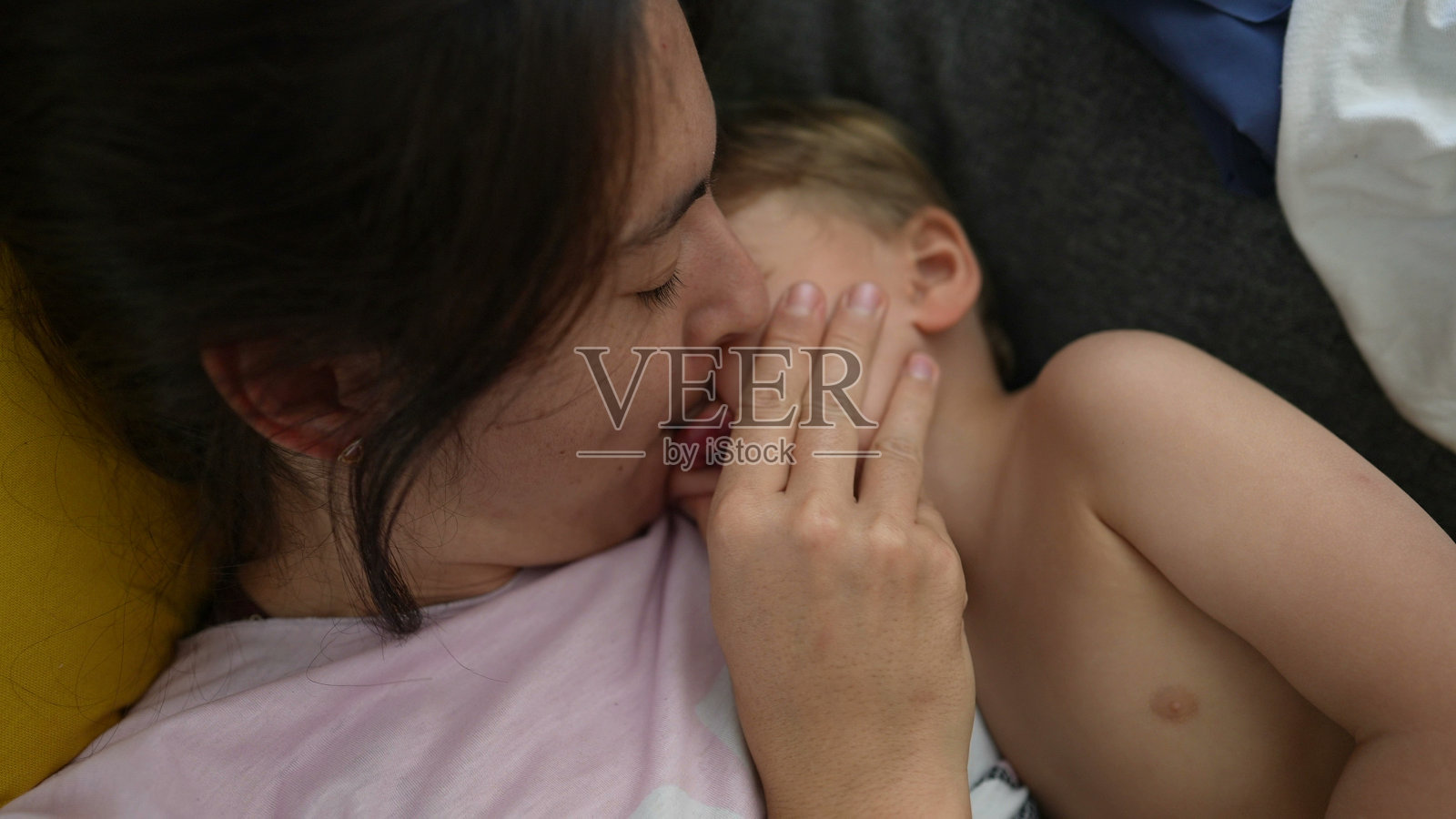 母亲亲吻蹒跚学步的孩子表达爱意照片摄影图片