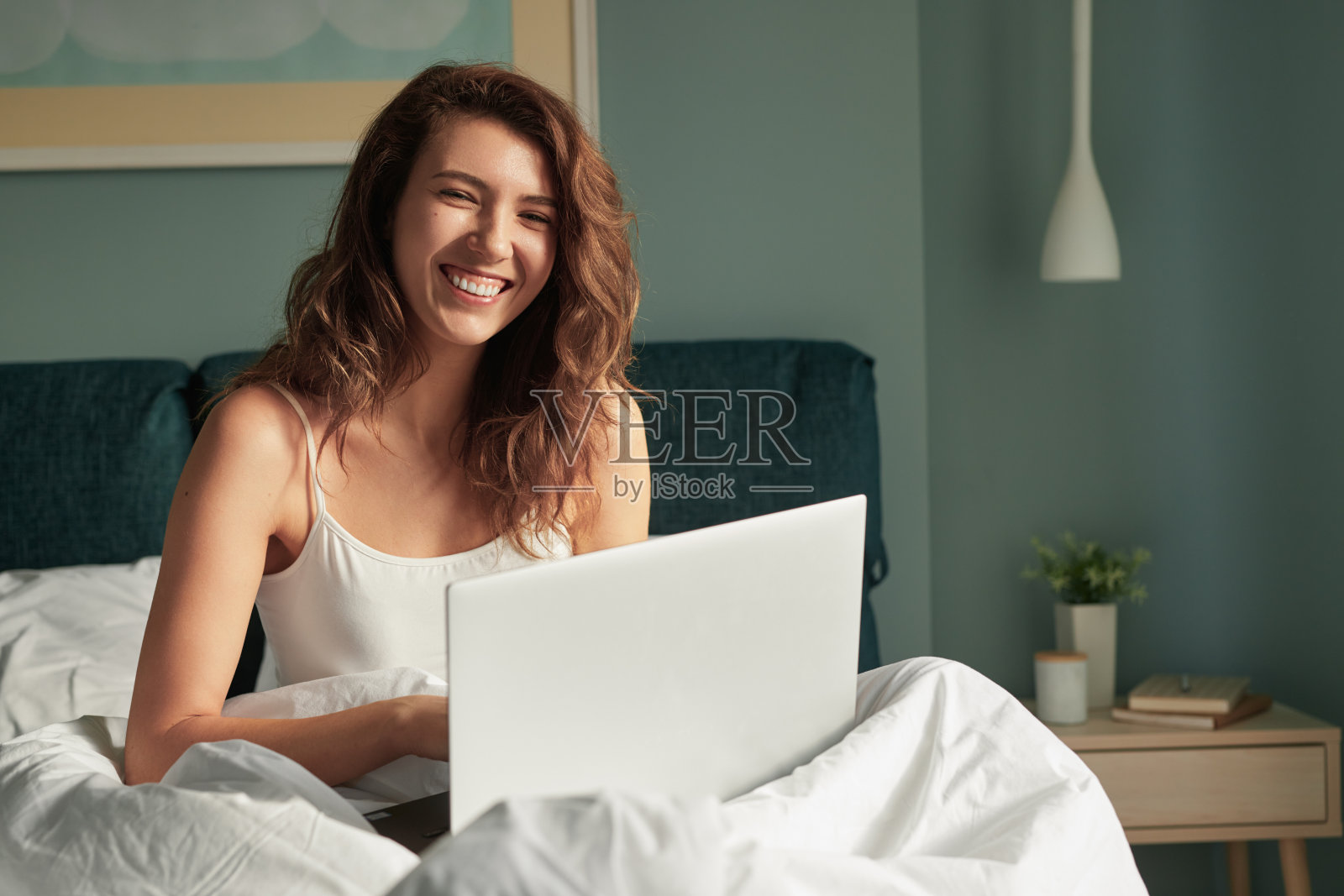 快乐的女人在床上用笔记本电脑照片摄影图片