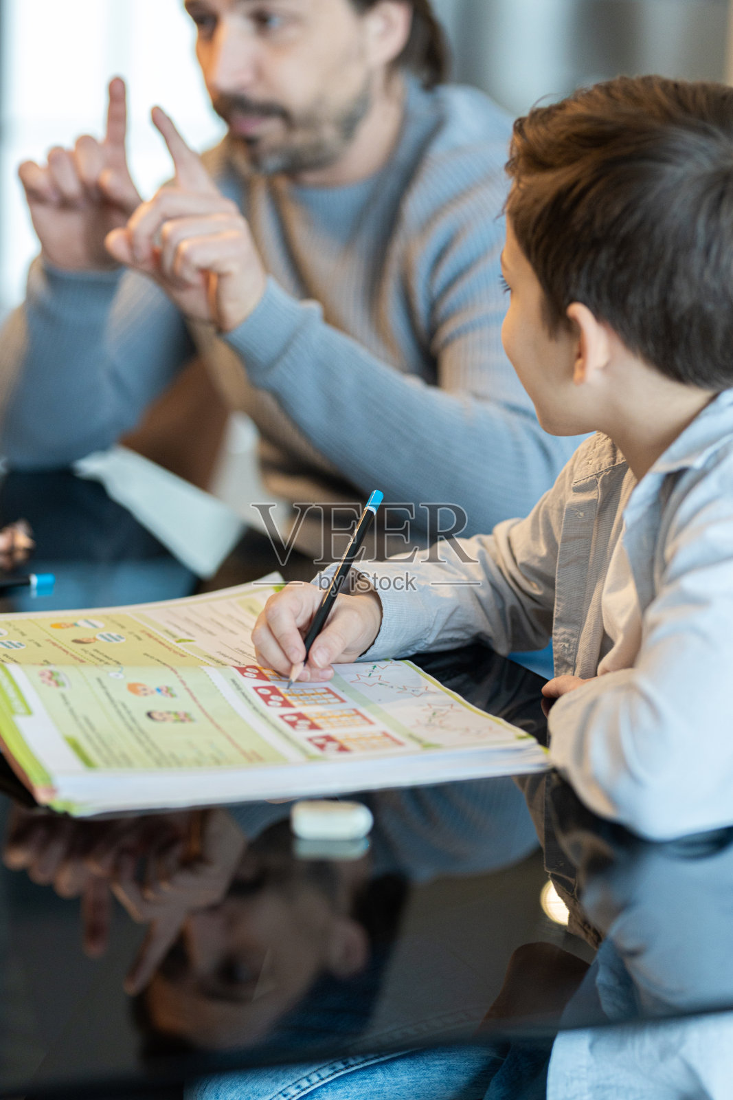 父亲和儿子在做家庭作业照片摄影图片