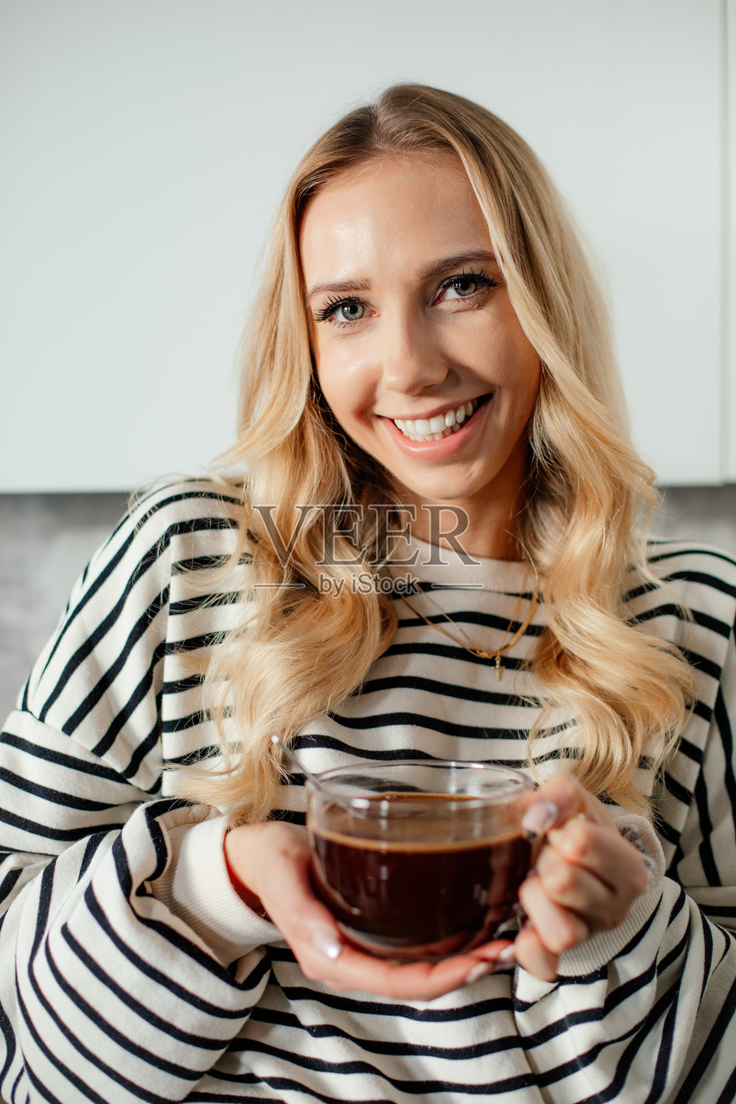 年轻高兴的金发微笑的女人的肖像，拿着一杯咖啡。照片摄影图片