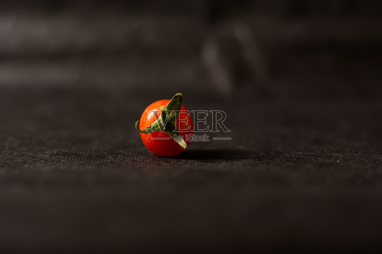 樱桃番茄在黑色的背景。前景是成熟的红色圣女果。照片摄影图片