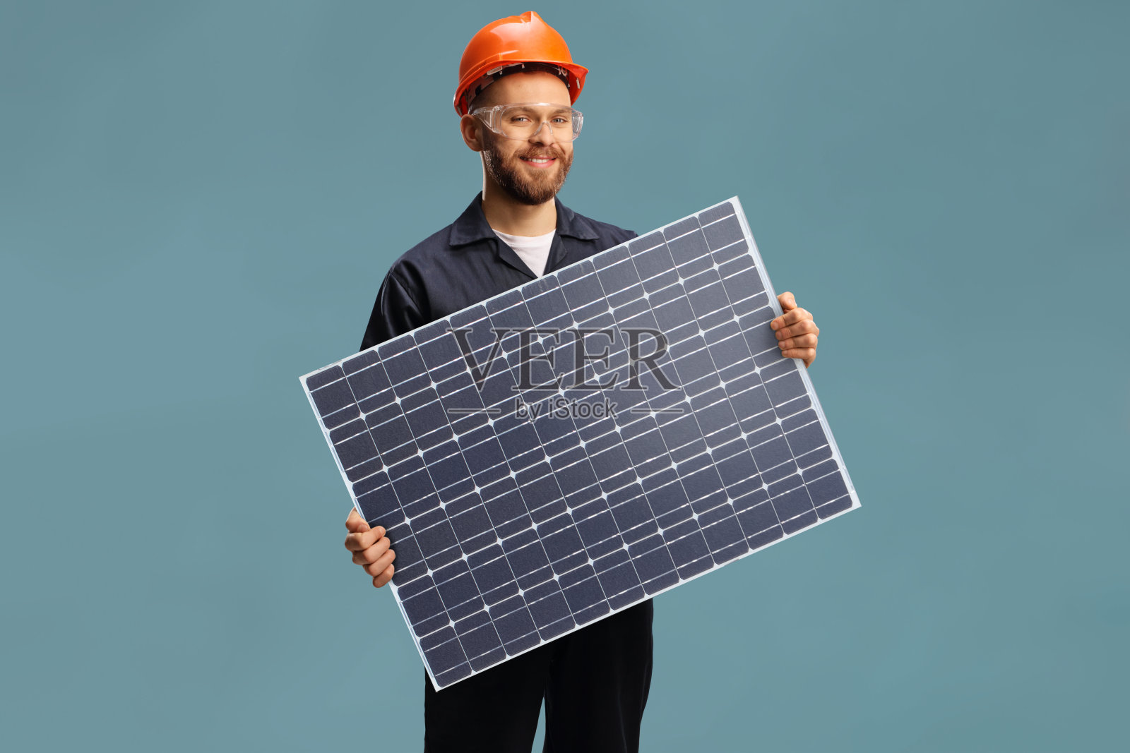 年轻的男性工人，穿着制服，手持太阳能电池光伏组件照片摄影图片