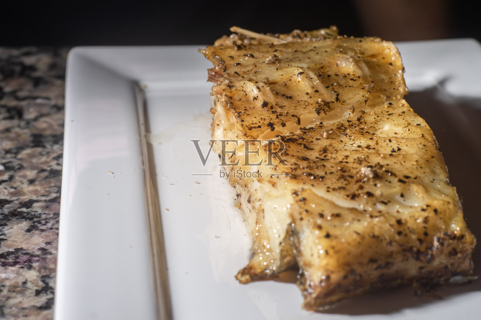 鱼切片和烤鳕鱼，在一个白色的盘子，复制空间和黑色的背景照片摄影图片