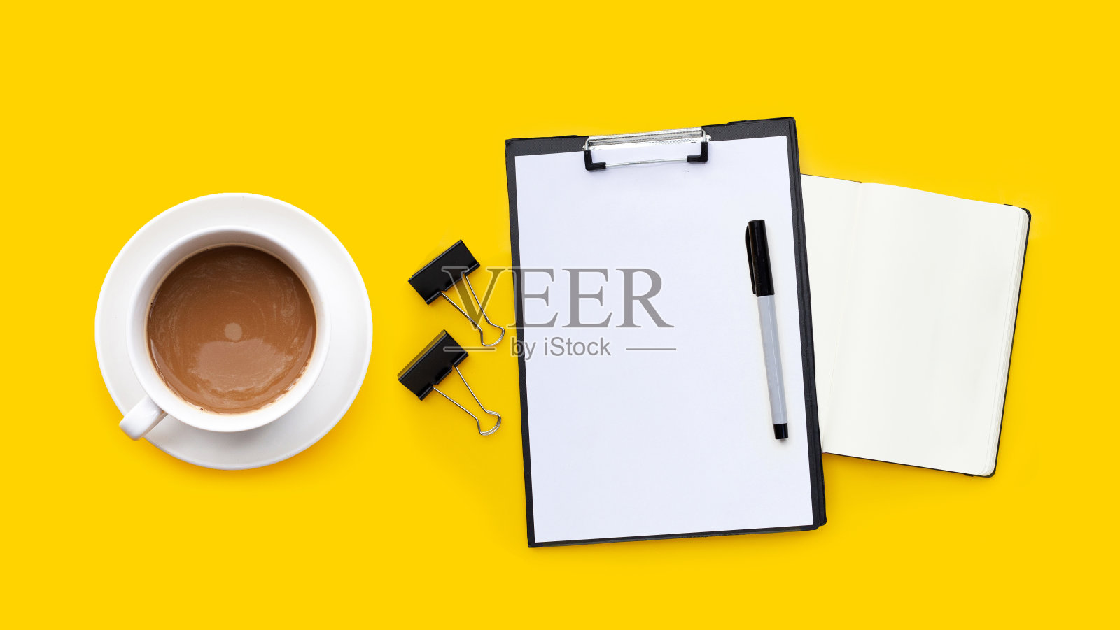 一杯咖啡，黄色背景的笔和笔记本。照片摄影图片