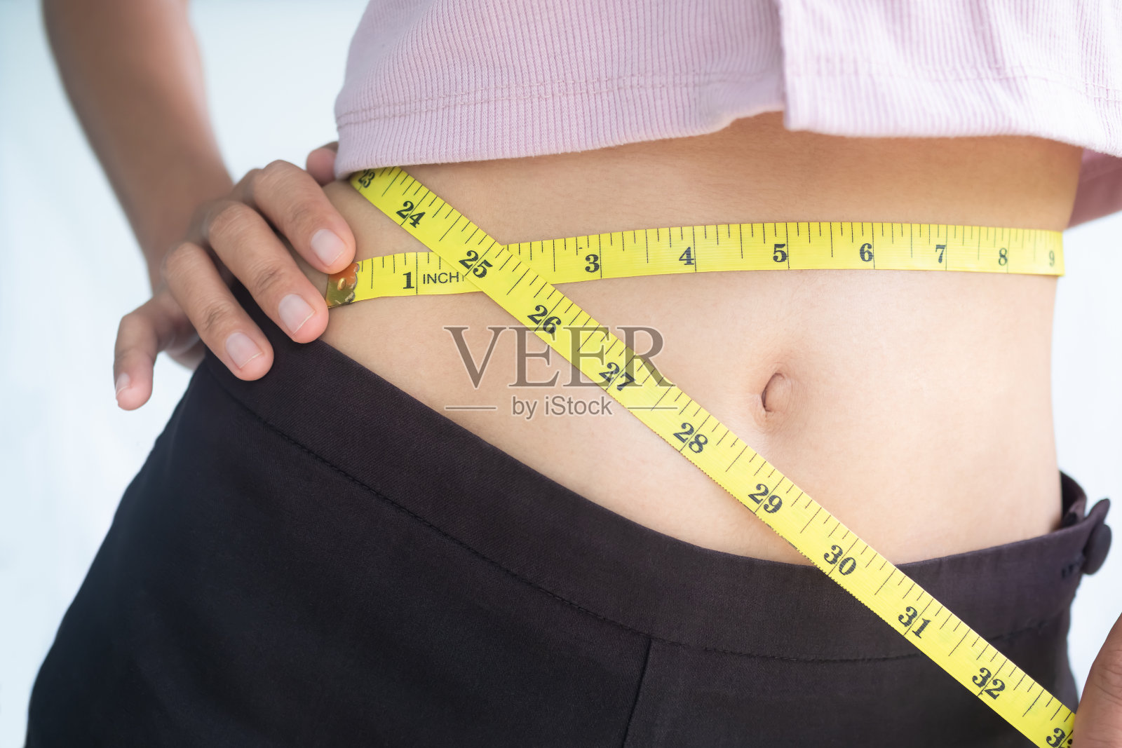 用卷尺量腰围的女人。照片摄影图片