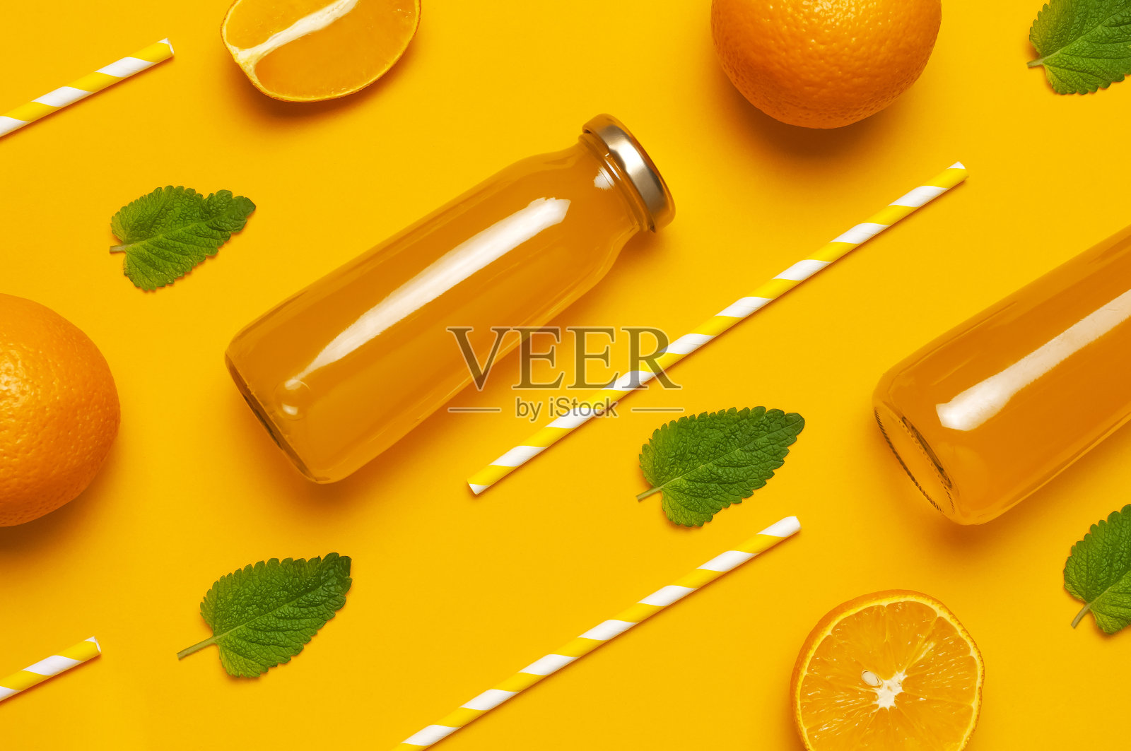 装有橙汁、新鲜甜橙、薄荷叶和黄色背景的饮用桶的玻璃瓶。健康食品，健康饮料，维生素c，创意夏季概念。平躺顶视图复制空间照片摄影图片