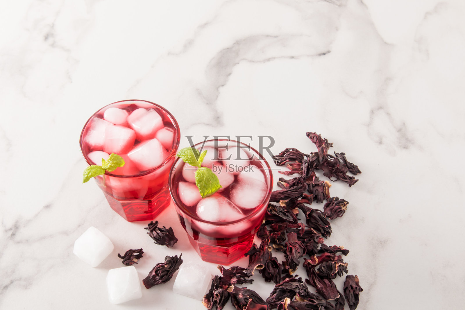 这是一种用木槿玫瑰花瓣、冰块、薄荷和干玫瑰花蕾制成的冷饮。照片摄影图片