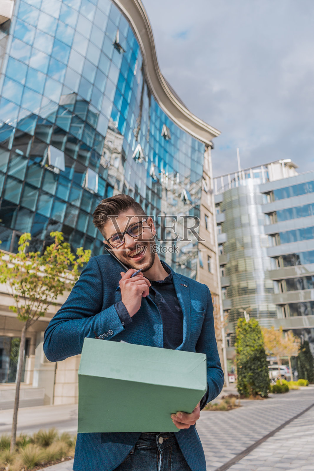 在户外，一个兴高采烈的年轻人一边用智能手机聊天，一边查看文件照片摄影图片
