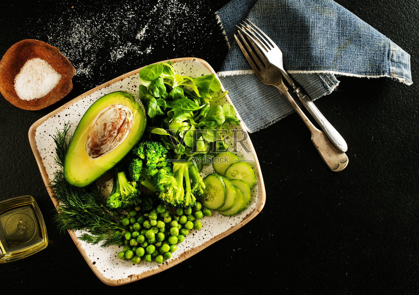 西兰花，青豆，黄瓜，鳄梨，罗勒和橄榄油的健康沙拉。健康食品。俯视图照片摄影图片