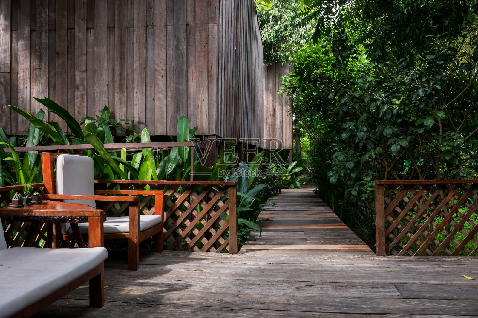 扶手椅和小屋在木制小径附近的春天花园照片摄影图片