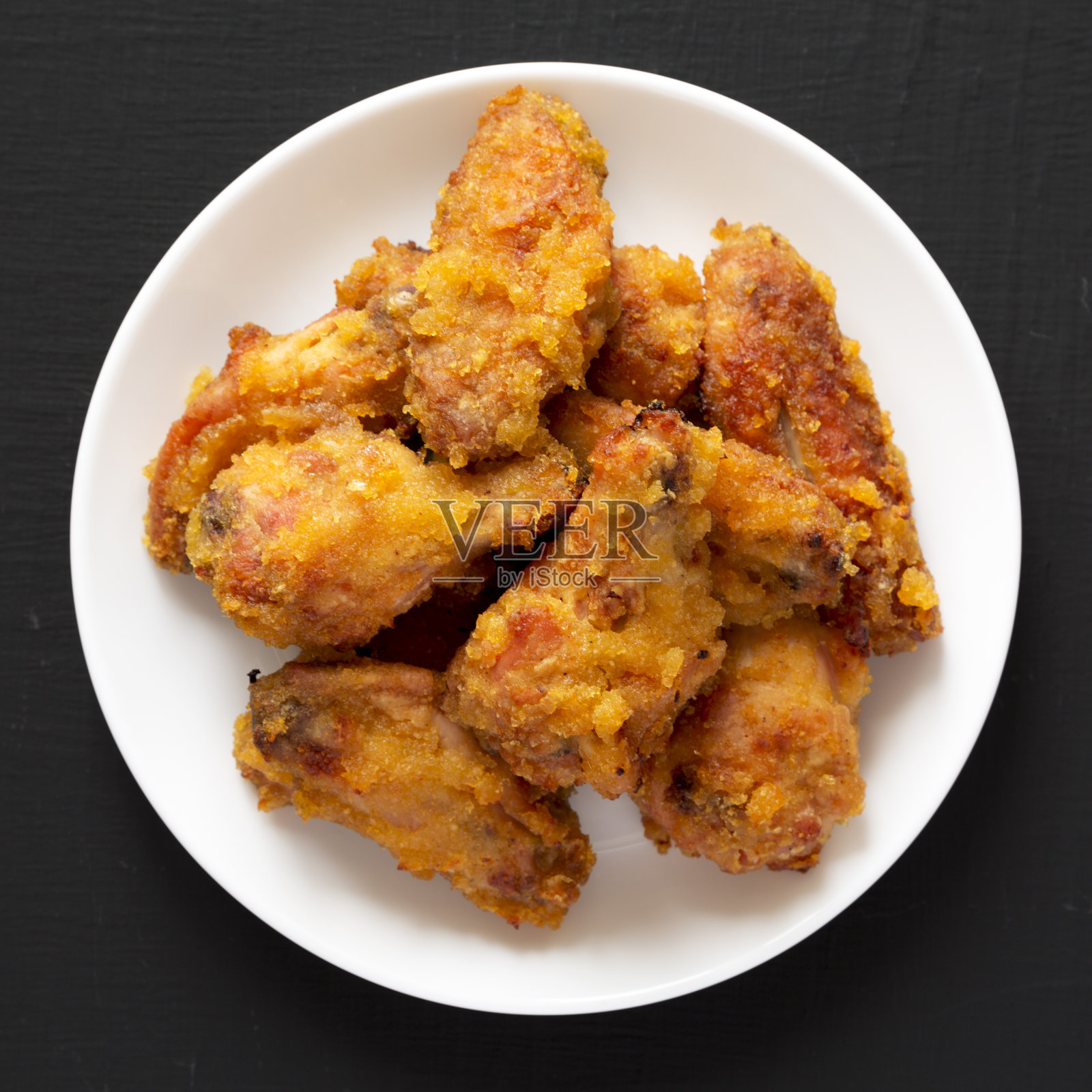 自制辣芒果鸡翅在黑色表面的白色盘子上，俯视图。平躺着，头顶上，从上面。照片摄影图片