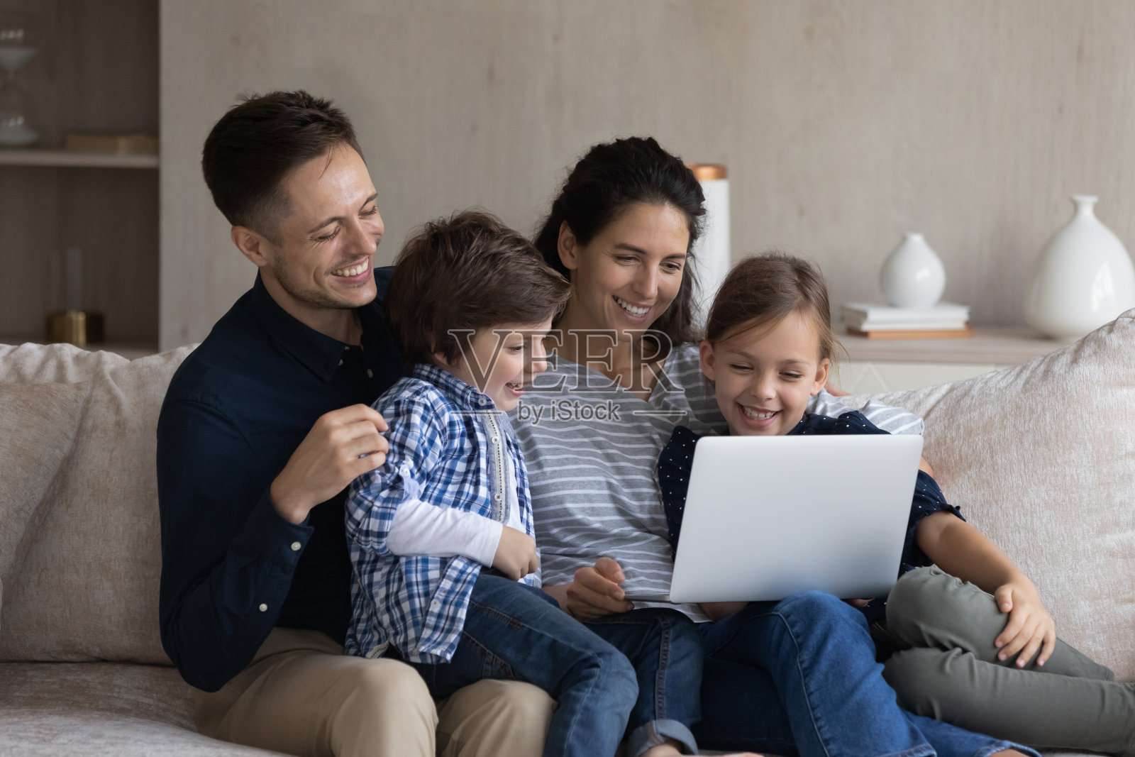 夫妇和孩子在沙发上用笔记本电脑看电影照片摄影图片