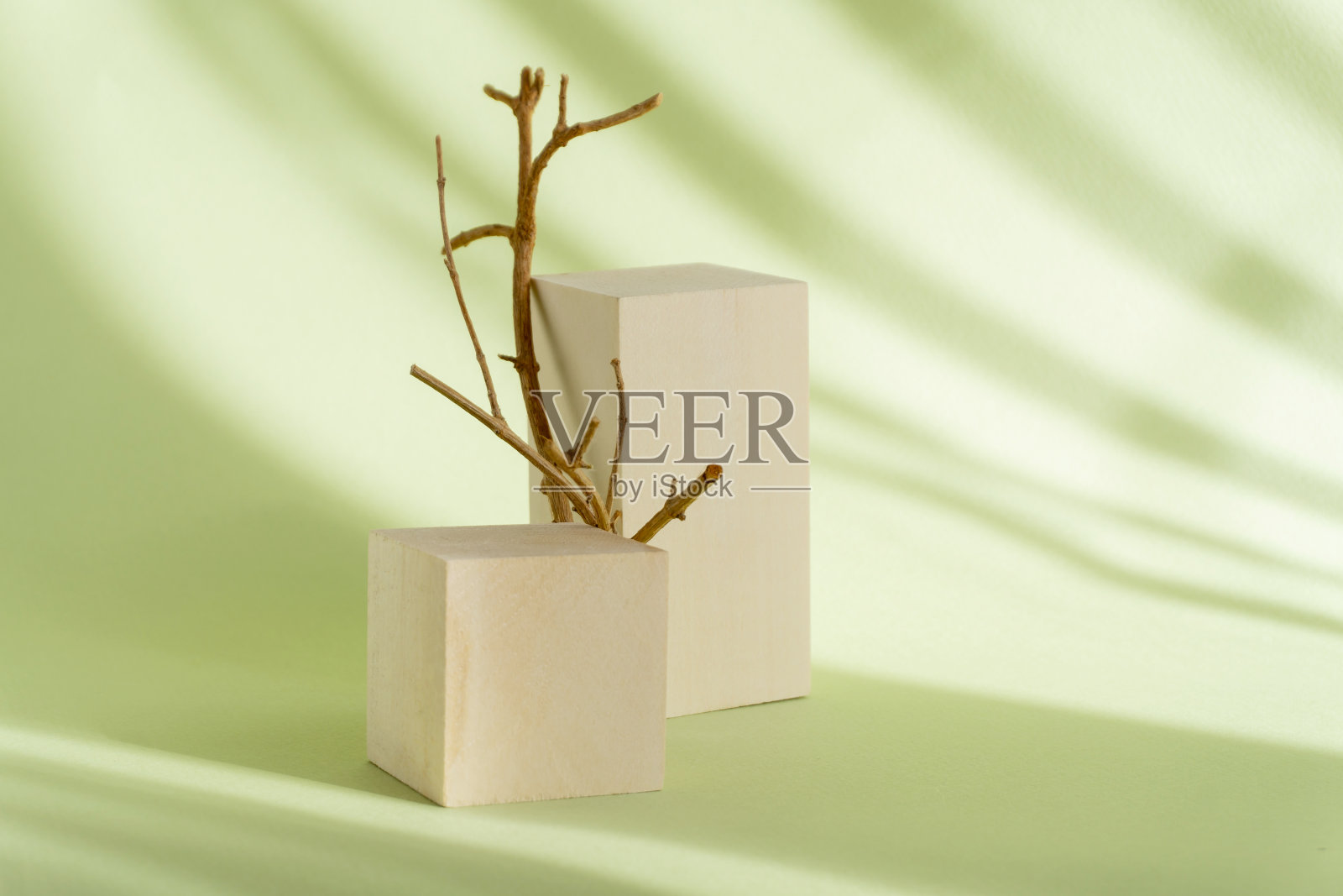 两个不同高度的木制几何支架展示了绿色纹理背景和条纹形式的阴影。3d讲台旁边的棕色障碍，为化妆品的介绍照片摄影图片