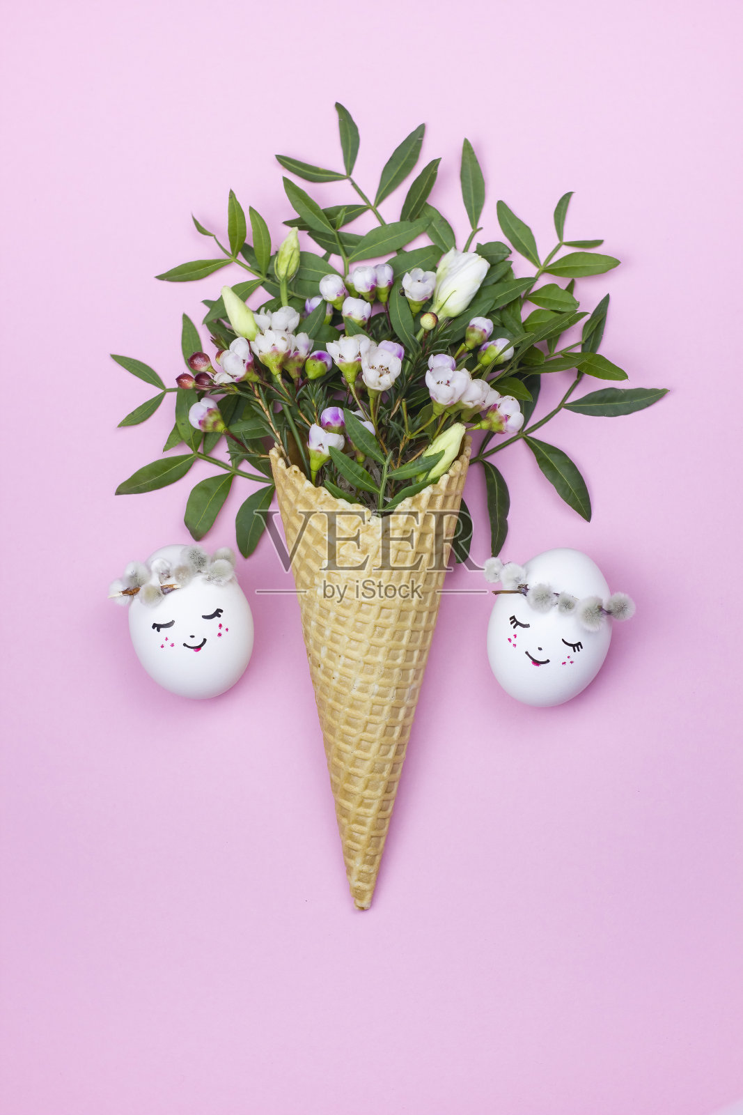 复活节彩蛋和华夫蛋筒与春天的花朵在粉红色的背景。照片摄影图片