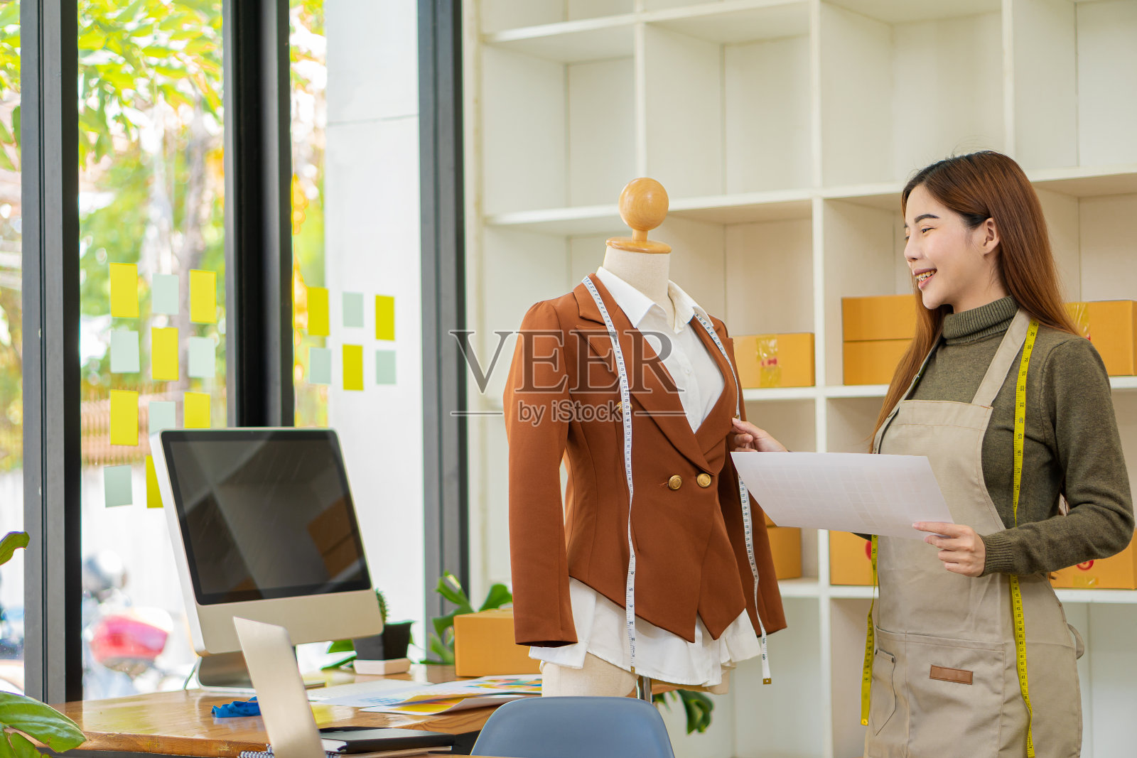 时尚设计师服装设计师站着用彩色的纺织品样品工作。用木偶和彩色织物工作。亚洲女企业家照片摄影图片