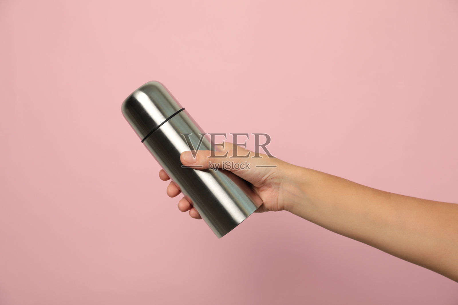 女人拿着现代热水瓶粉红色的背景，特写照片摄影图片
